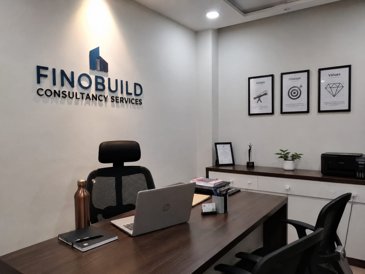 The Finobuild Consultancy Services office reception, with the company's vision, mission and values framed on the wall.